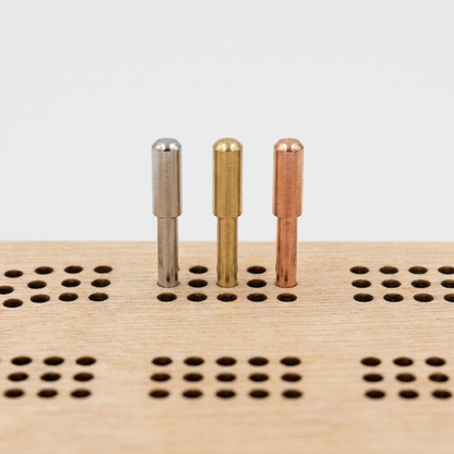 Minnesota-shaped cribbage board - close-up of silver, brass, and copper metal cribbage pegs in the peg track, studio detail shot